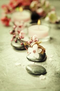 Spa setting. Massage stones, Sea salt, candles and flowers on rustic background