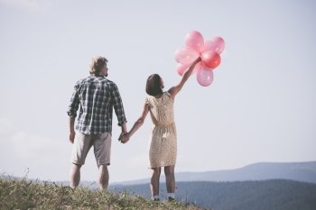Young loving couple with balloons on sky background