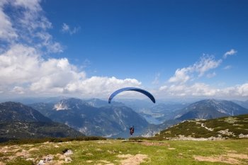 Parachute jumping extreme sport. Paraglider flying over mountains in summer day