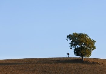 Photographer on the hill over blue sky