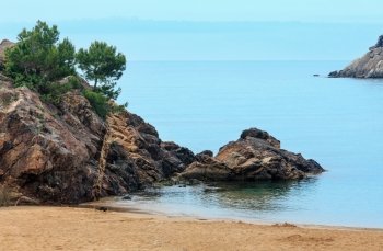 Rock formations with pine trees on sandy La Fosca beach, Palamos, Girona, Costa Brava, Spain.