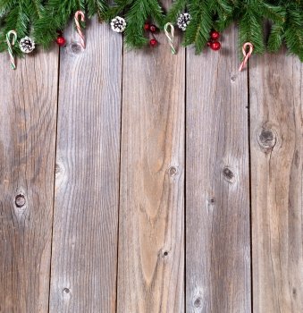 Wooden background for Christmas concept with fir branches, candy canes and red berries. Overhead view with copy space.