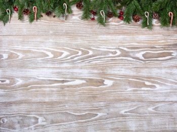 Rustic white wooden background for Christmas concept with fir branches, candy canes and pine cones. Overhead view with copy space.