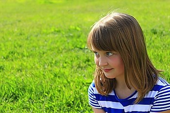 portrait of girl on the green grass background. little fashionable girl smirks on the green grass background