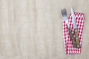 The background for the menu. Canvas tablecloth, fork, knife and napkin for steaks. Is used to create a menu for a steak house.