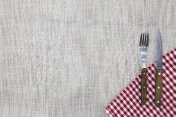 The background to create the restaurant's menu. Linen tablecloth fork knife on a bright checkered cloth. Is used to create a menu for the steak restaurant