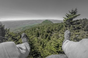 Hiker legs and boots view on the mountain peak relaxing outdoor mountain sport