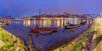 Rabelo boats on the Douro river, Porto, Portugal.. Panoramic view, traditional rabelo boats with barrels of Port wine on the Douro river, Ribeira and Dom Luis I or Luiz I iron bridge on the background, Porto, Portugal.