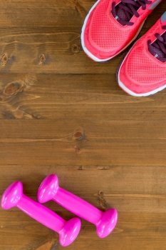 pink sneakers and a dumbbell in the corners of the frame on the wooden floor