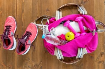 open sports bag and pink running shoes on a wooden floor top view