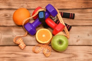 The concept of a healthy lifestyle, sports and diet. Dumbbells, smart watches, fruit, measuring tape