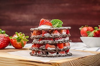 Chocolate belgian waffles with strawberries, whipped cream and mint leaf on wooden table