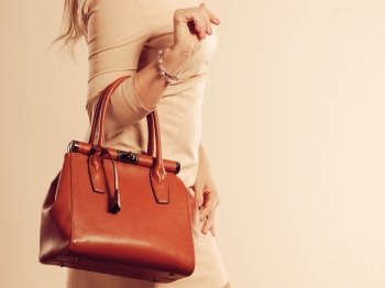 Beauty and fashion. Stylish fashionable woman wearing bright dress holding brown bag handbag, studio shot toned image
