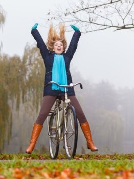 Active woman having fun riding bike in autumn park. Happy carefree active woman having fun riding bike bicycle in fall autumn park. Crazy young girl relaxing. Healthy lifestyle and recreation leisure activity.
