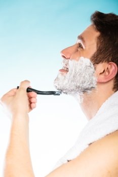 Young man shaving using razor with cream foam.. Young man shaving using razor with cream foam. Handsome guy removing face beard hair. Skin care and hygiene.