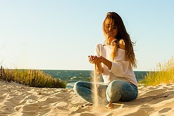 Young joyful girl on beach.. Joy and carefree. Gorgeous long haired woman having fun with sand on beach. Young joyful attractive girl feels freedom. 