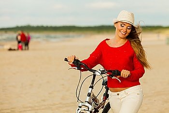 Beauty tourist with bike on beach.. Sports and recreation. Attractive smiling woman with bicycle walks on beach near to sea. Young long haired gorgeous tourist spends time on seaside.