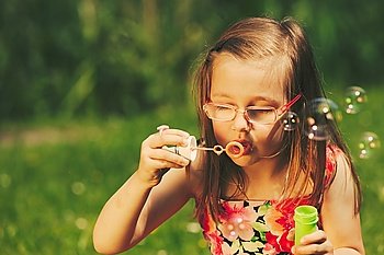 Little girl child blowing soap bubbles outdoor.. Little girl child blowing soap bubbles outdoor. Kid having fun in park. Happy and carefree childhood. Instagram filtered.