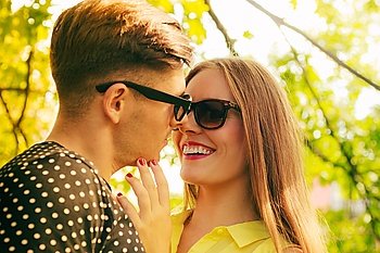 Smiling couple in park. Love and happiness. Young happy joyful couple lovers wearing sunglasses dating in summer park outdoor.