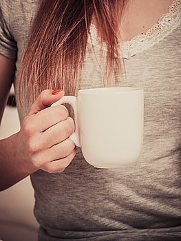 woman on bed with cup of coffee. Woman relaxing at cozy home atmosphere on the bed. Female with red nails manicure holds cup of coffee in hands enjoying comfort