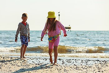 Kids playing outdoor on beach.. Joyful active childhood. Playful kids playing near water on seaside. Children having fun on summer beach. Young tourists spending actively time.