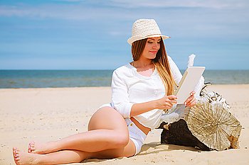 Young pretty woman with tablet pc computer on beach. Technological resting, summer, vacation.