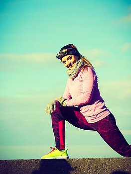 Woman fitness sport girl training outdoor in cold weather. Woman athlete girl training wearing warm sporty clothes outside by seaside in cold weather. Sports and activities in winter or autumn time.