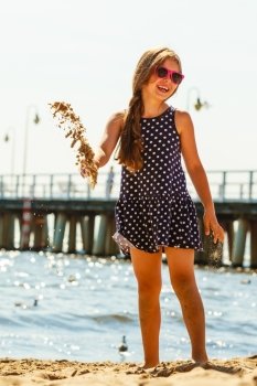 Girl having fun on beach.. Joy and fun. Lovely little girl wearing summer clothes having fun outside on beach seaside. Child spending time playing near to sea ocean.