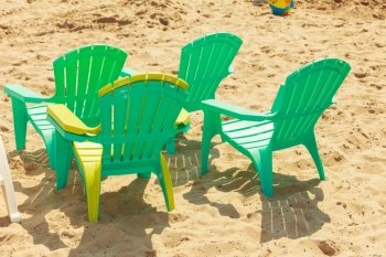 Green plastic chairs on sand.. Rest and relax in summer. Four green plastic chairs on sand. Relaxation place on sunny beach.