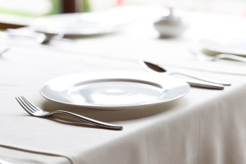 White plate with knife and fork on decorated table. White plate with knife and fork
