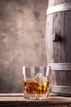 Glass and a barrel of whiskey on wooden table. Glass and a barrel of whiskey