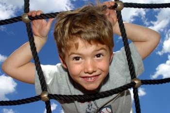 Portrait of a boy climbing up a net