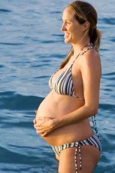 Side profile of a pregnant woman touching her abdomen