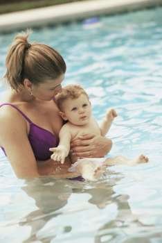 Side profile of a mother playing with her baby boy in a swimming pool