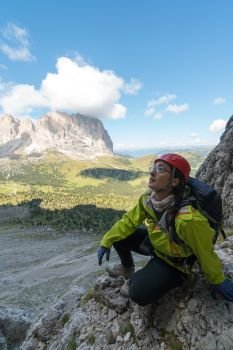young attractive female mountain climber in the Dolomites of Italy with a great  view of the Langkofel and Passo Sella
