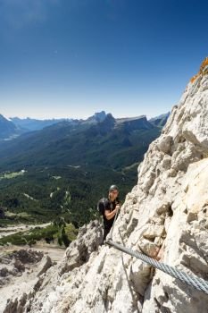 attractive blonde female mountain climber on a steep Via Ferrata in the South Tyrol