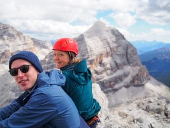 portrait of mountain climber couple in their twenties enjoying a break on the top of a mountain in the Italian Dolomites