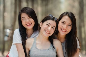 Teenage Asian female happy smiling to camera, Group of young Asian friends camping or picnic together in forest. Women do adventure activity and travel on holidays vacation in summer.