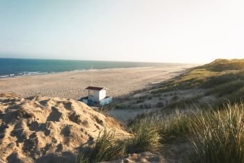 Summer vacation at the beach in the morning light with beach, marram grass, dunes, lifeguard house and sea, on Sylt island, Germany, at the North Sea