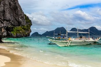 Tropical island landscape with bangca traditional phillipinians boats anchored at the shore, Palawan, Philippines