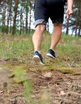 adult man in black shorts runs in the coniferous forest, concept of a healthy lifestyle and running in the fresh air