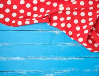 red textile towel with white circles on a blue wooden background, kitchen picnic background, copy space