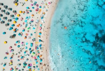 Aerial view of sandy beach with colorful umbrellas, swimming people, sea coast with transparent blue water at sunny day in summer. Travel in Mallorca, Balearic islands, Spain. Top view. Tropical 