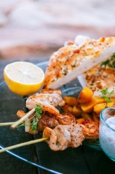 Shrimps and chicken Piri Piri African style Barbecue skewers with flatbread on glass plate close up image