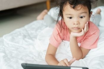 Asian girl are watching video that are exciting on online media. The little girl use the tablet to watch video for home entertainment.
