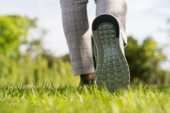 Woman’s legs wear sports shoes, Jogging on the green grass in the park at morning, Healthy lifestyle concept 