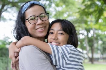 Asian mother and daughter hug each and smiling  other at the park, Happy family concept.