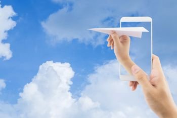 Hand with paper plane with mobile phone against blue sky sending email, communication concept. 