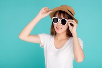 Beautiful portrait young asian woman wear hat and holding sunglasses smiling confident enjoy journey summer trip in vacation isolated on blue background, tourist asia girl cheerful with travel.