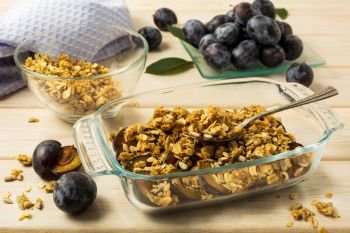 Healthy breakfast fresh plum granola in the glass baking tray